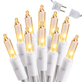 Brizled clear Christmas lights wrapped around a tree with warm glow