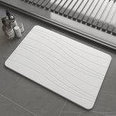 Drvykkn fast drying stone bath mat showing absorbency in a modern bathroom