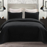 Exclusivo Mezcla reversible quilt set on a black queen bed for all-season comfort
