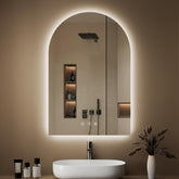 OUMUSU arched backlit mirror with ambient lighting enhances bathroom ambiance.