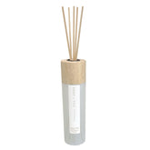 Sand + Fog Ocean Mist diffuser bottle with reeds releasing fragrance in a room