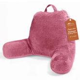 Sasttie Reading Pillow with arms in rose pink resting on a bed for upright reading.