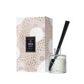 Voluspa Santal Vanille diffuser in glass vessel enhances living room ambiance.