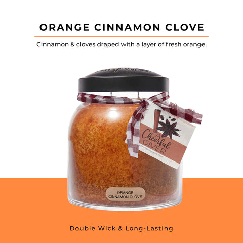 A Cheerful Giver orange cinnamon clove candle lit on a rustic table for cozy ambience.
