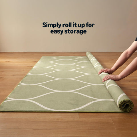 Rug laid in a living room with green geometric design by Amazon Basics