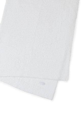 Barefoot Dreams CozyChic Throw cream in bed, soft warmth for cozy nights.