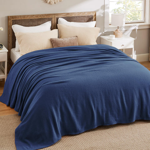 Soft and breathable cotton blanket drapes over bed for everyday comfort.