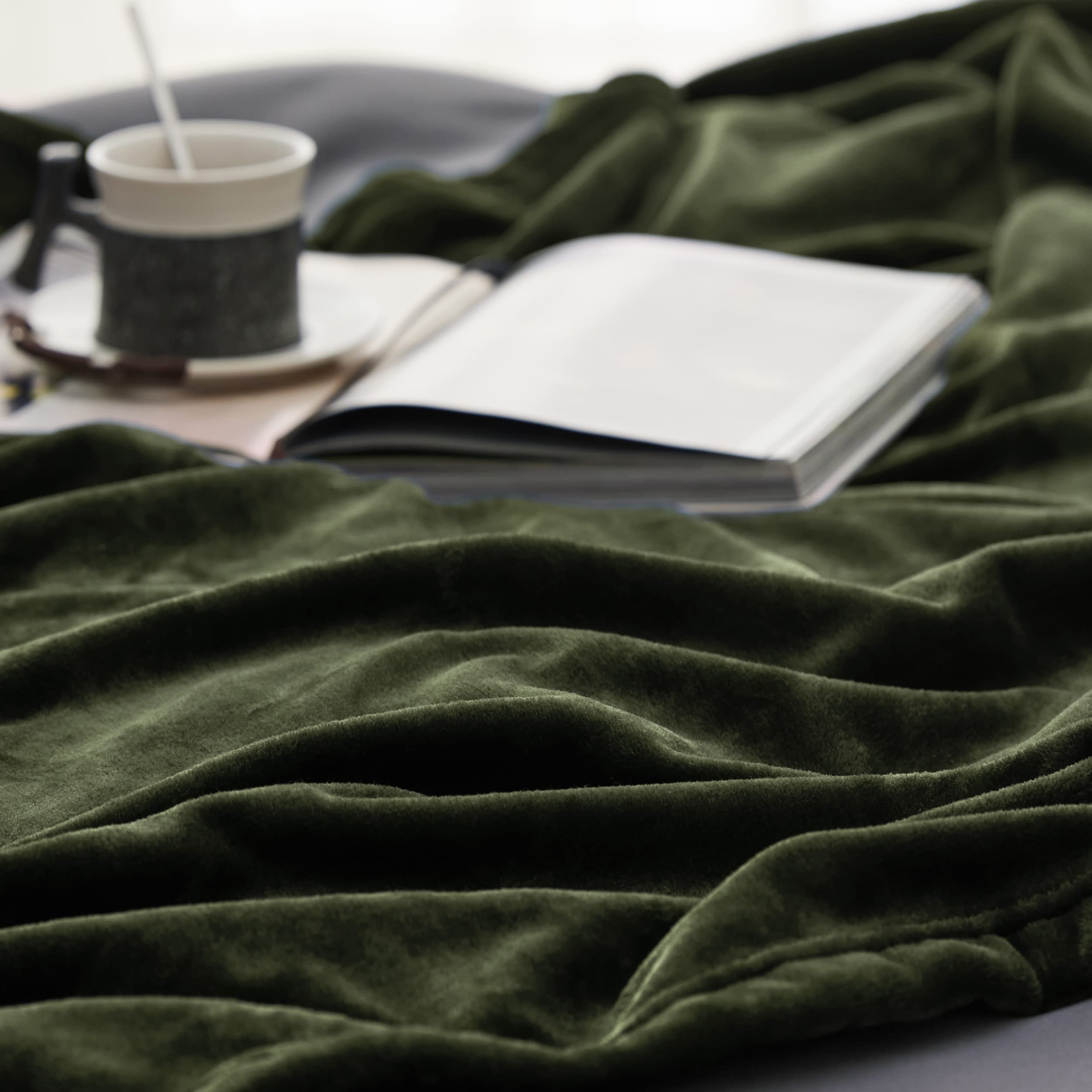Bedsure olive-green blanket on sofa provides lightweight warmth for evenings.