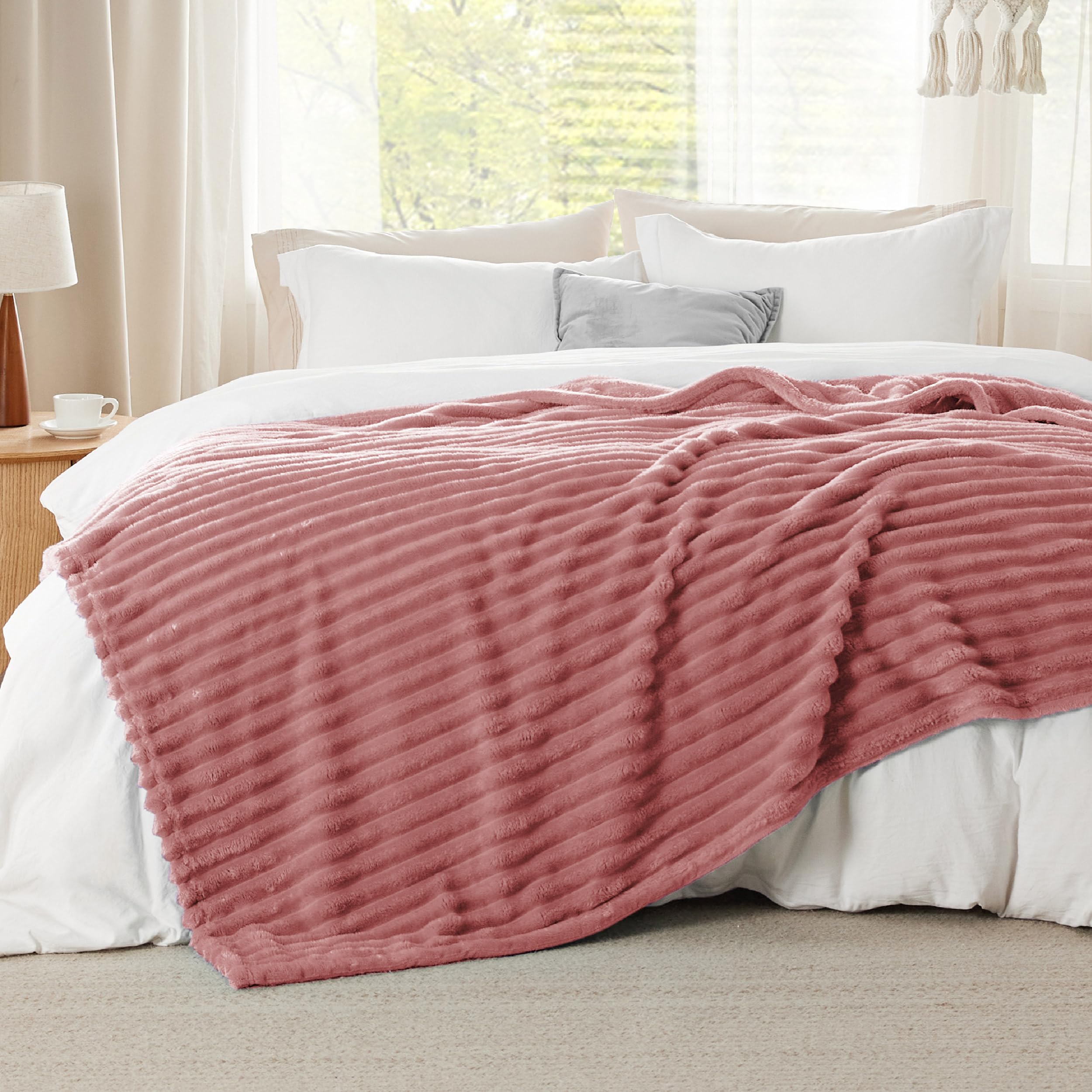 Bedsure GentleSoft dusty pink fleece blanket draped on a sofa to show warm yet lightweight comfort.