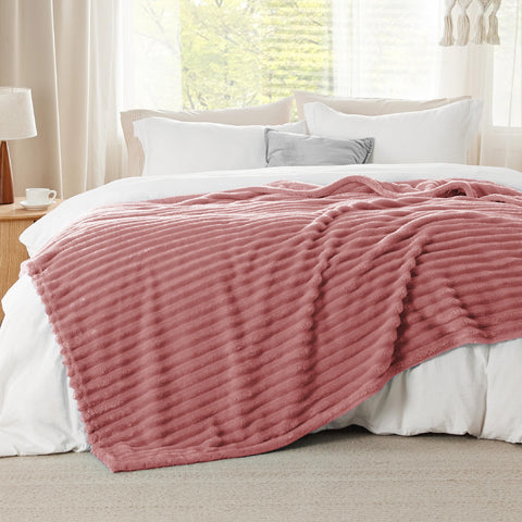 Bedsure GentleSoft dusty pink fleece blanket draped on a sofa to show warm yet lightweight comfort.