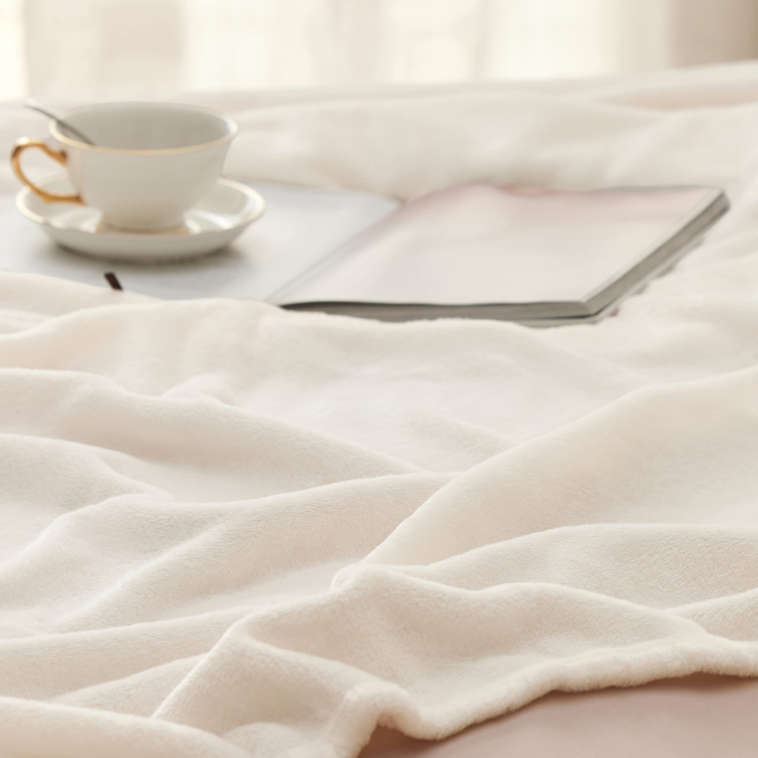 Bedsure GentleSoft blanket cream draped on sofa, providing lightweight warmth.