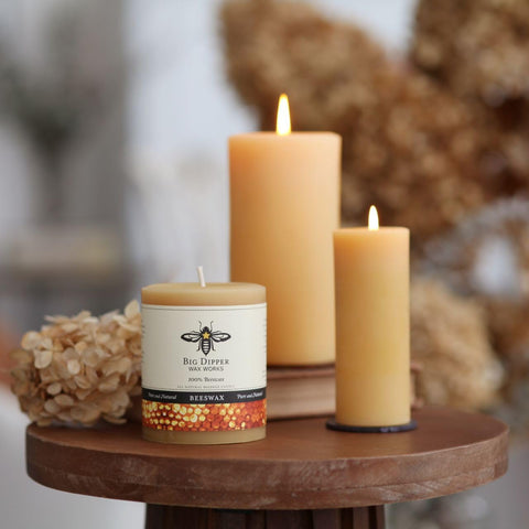 Big Dipper Wax Works beeswax pillar candle in rustic setting, handmade and eco-conscious.