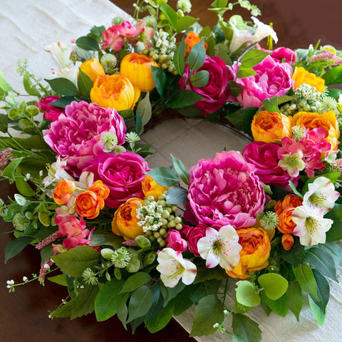 CHvista wreath with coral-orange and ivory blooms creates a vibrant porch backdrop.