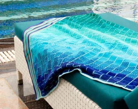 Cotton Craft towel folded on sand shows vibrant color retention in sun.