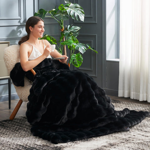 Cozy Bliss black 50x60 inch throw drapes over a sofa.