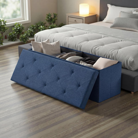 DUMOS blue ottoman in a bedroom setup offering extra seating and storage.