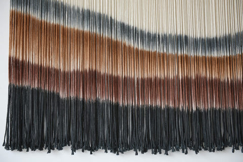 Flber macrame wall hanging above bed adds inviting, intimate ambience.