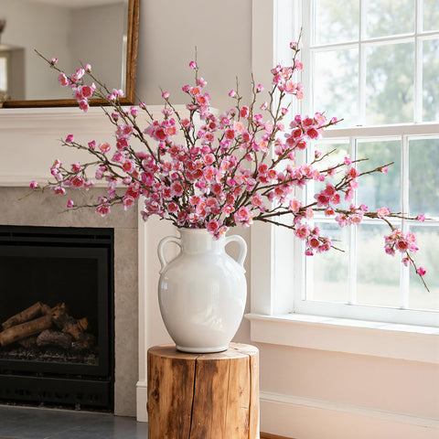 Florisso pink cherry blossom branch in bedroom corner for soft ambiance.