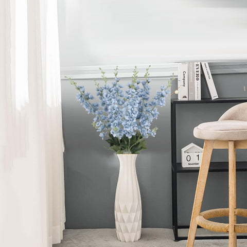 Fqueelvys delphinium stems arranged on a dining table centerpiece