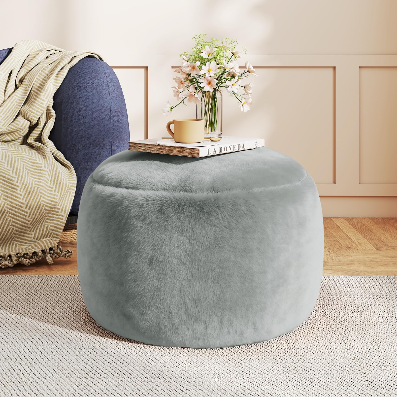 Gericco round pouf ottoman in gray, plush foot rest beside the sofa for relaxation.