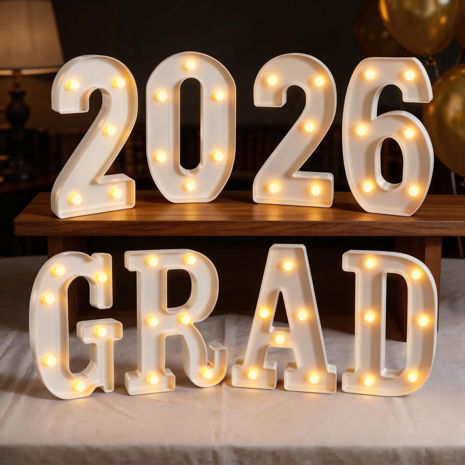 Glimmrly Grad LED letters illuminate a table centerpiece for a graduation setup.