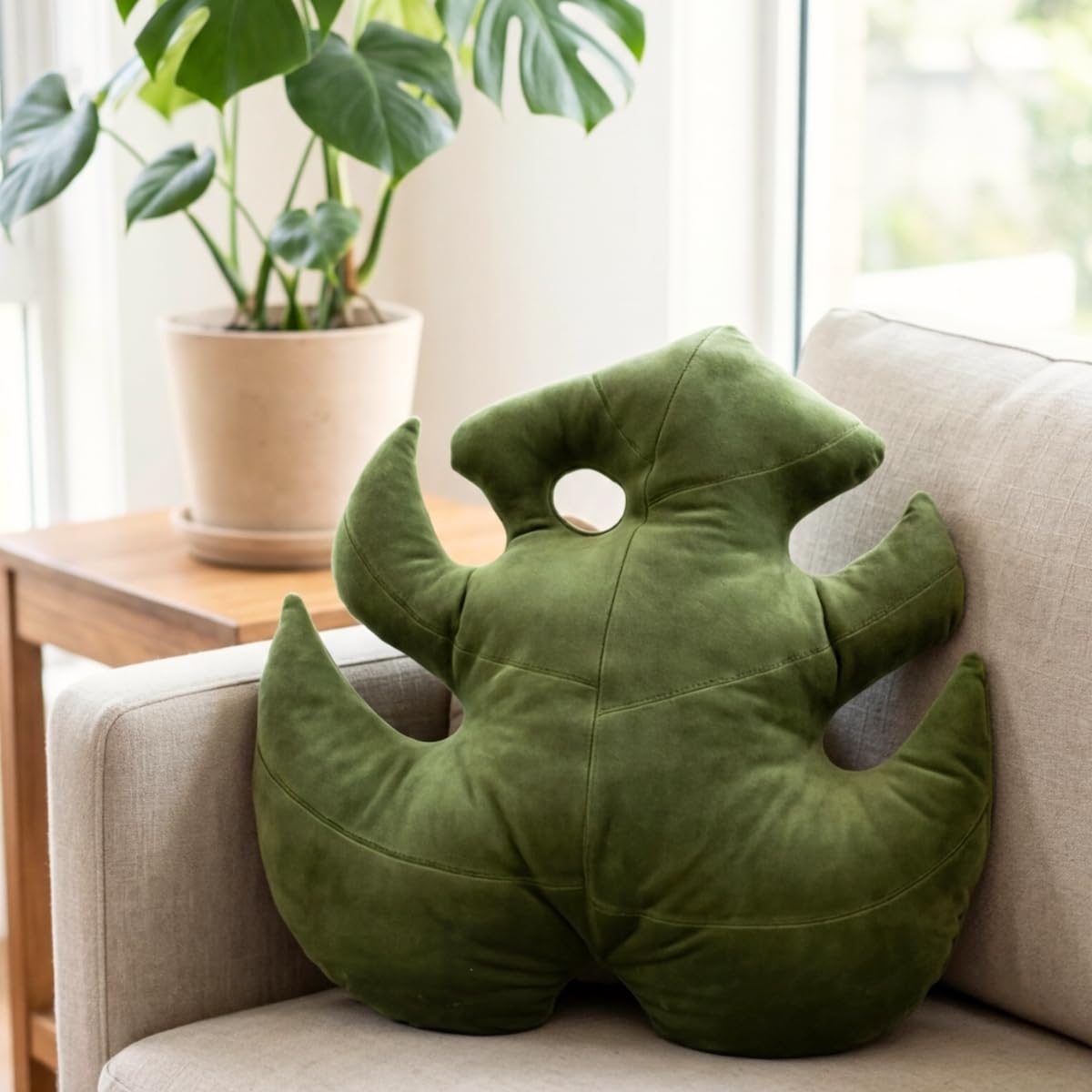 Green Philosophy Co. Monstera Leaf Pillow on couch corner adds tropical flair and support.