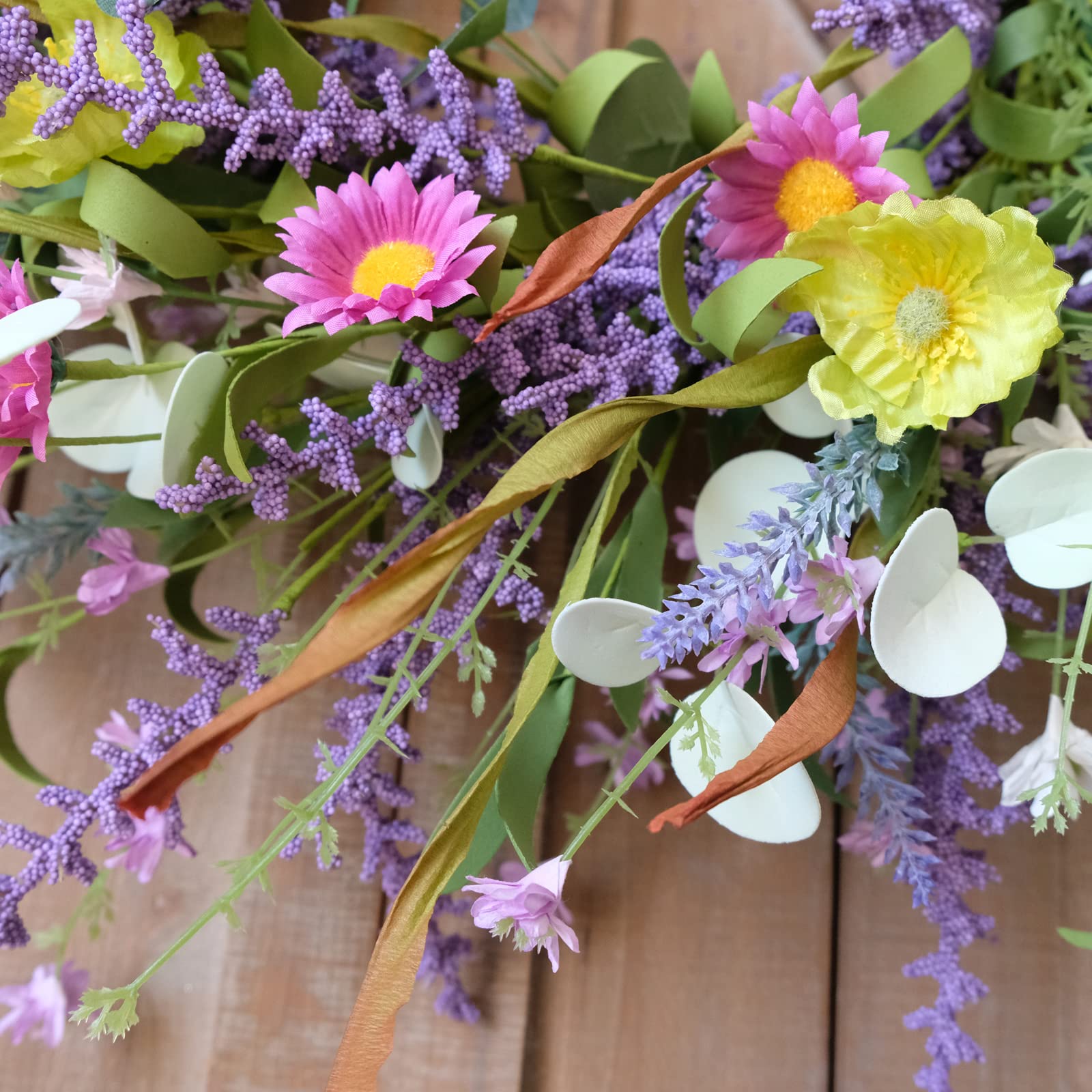 Idyllic greenery flower wreath blends greens and spring flowers for a lively welcome.