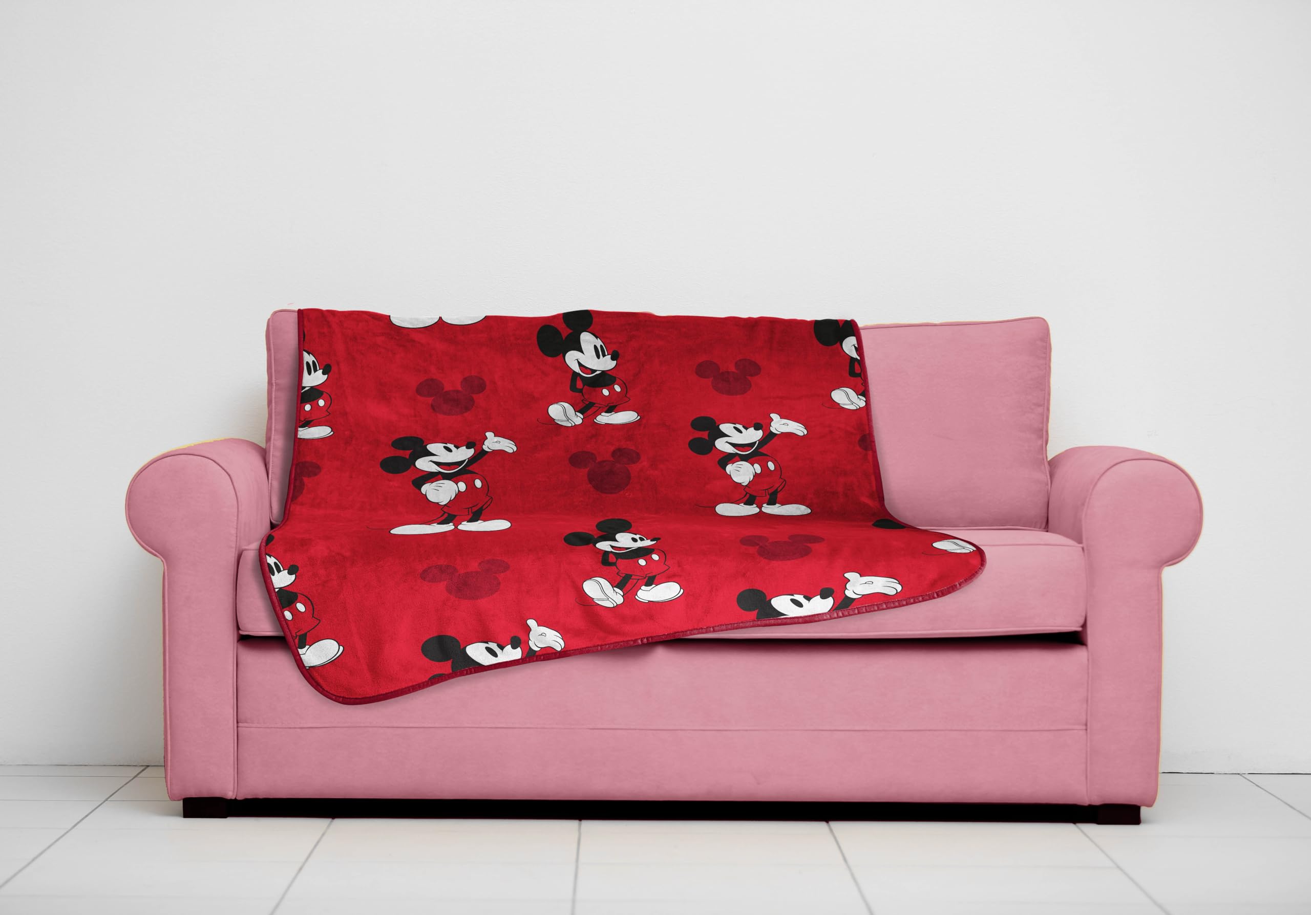 Jay Franco Mickey Mouse plush throw on a couch, ideal travel companion.