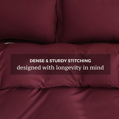 Two matching pillow shams with the JSD Burgundy 3-piece set on bed