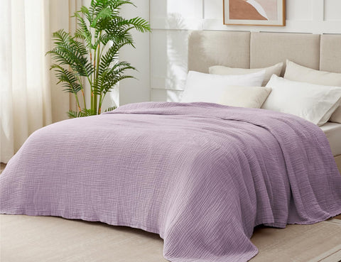 Kozyhvn lavender muslin blanket on bed highlighting breathable six layer design.