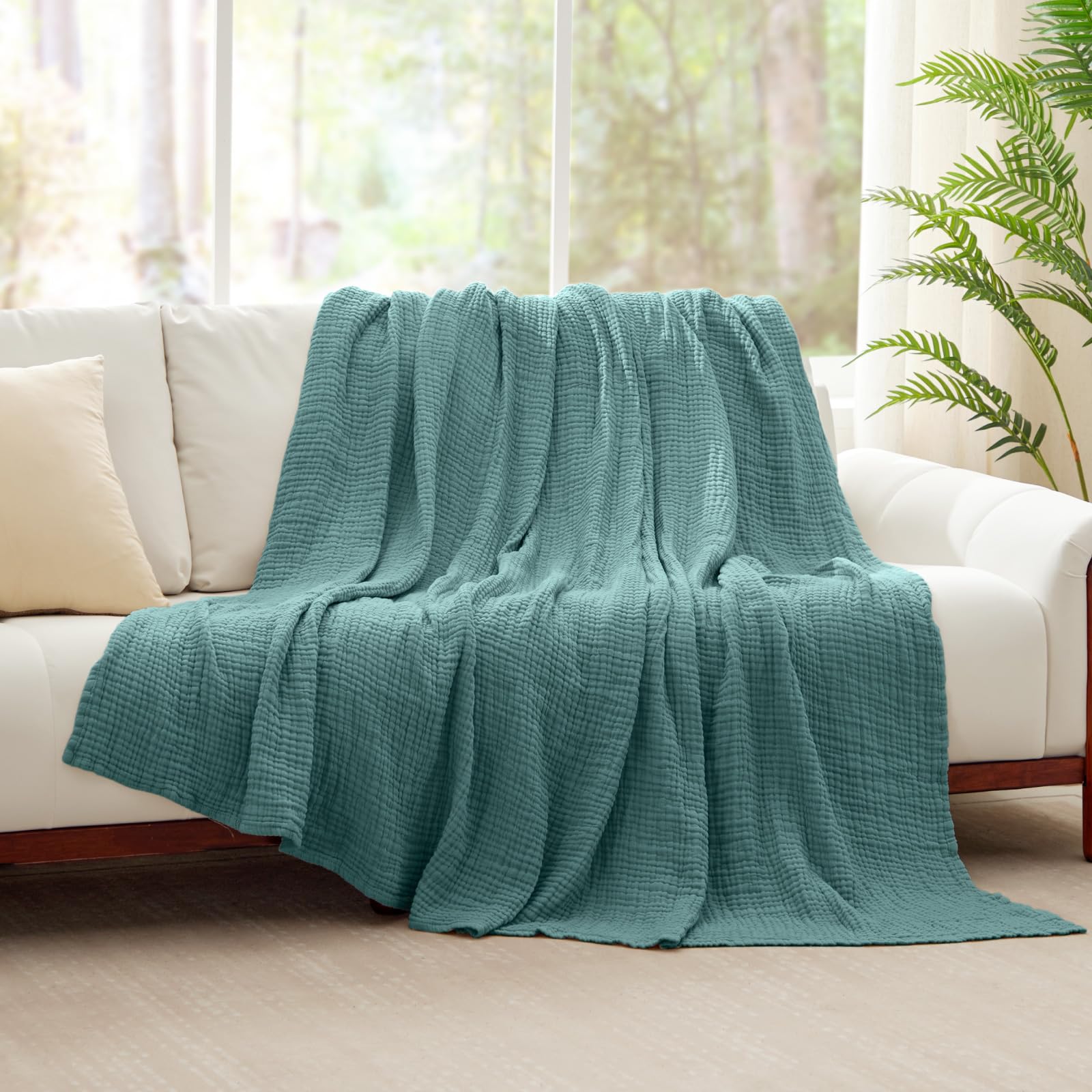 Kozyhvn teal muslin blanket on couch adds versatile warmth.