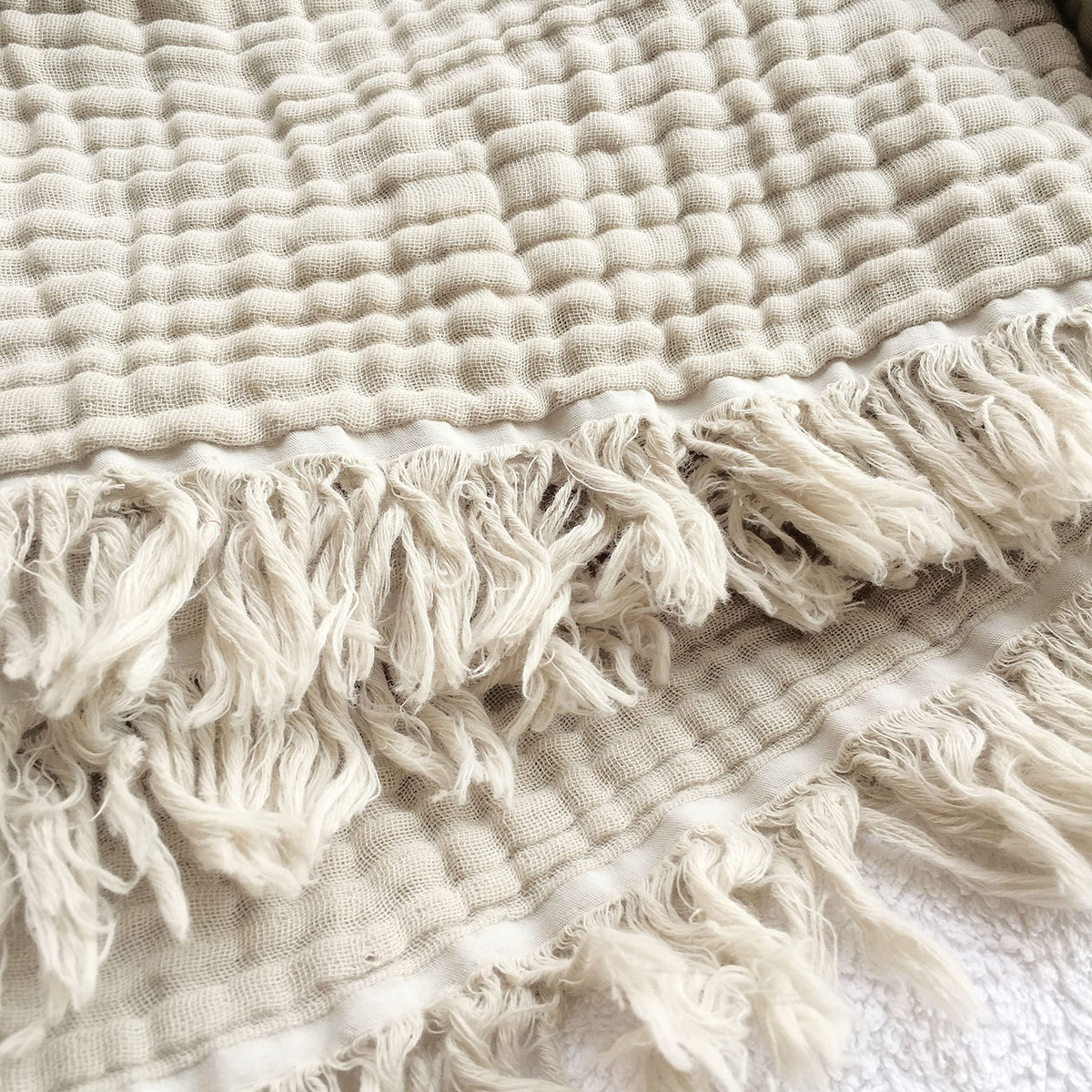 KyraHome muslin blanket folded in oatmeal khaki for cozy display.