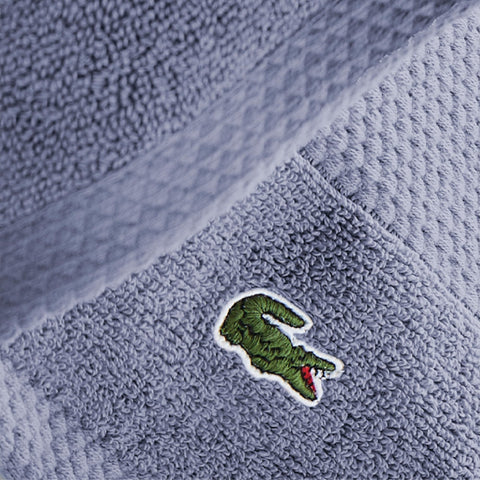 Lacoste Croc logo on the towel surface signals premium branding.