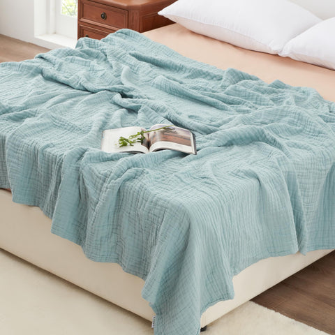 Love's cabin blanket in beige on a bed shows breathable 6-layer muslin comfort for all seasons.