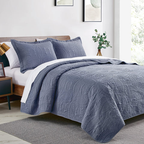 Close-up of Love's cabin blue quilt showing embossed coin pattern and soft texture.