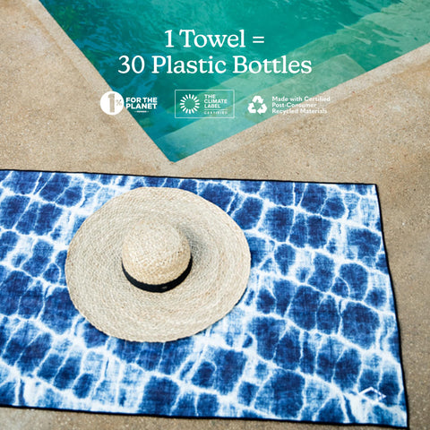 Nomadix Original Towel beside a poolside chair with a damp surface.