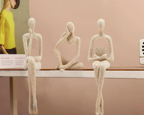 Three-piece gold thinker statues arranged on a desk for focus
