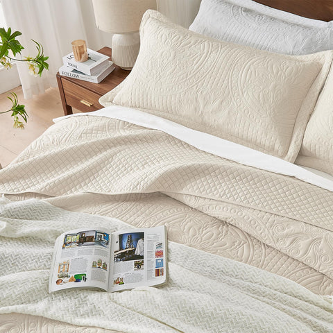 Qucover oversized king bedspread in beige styled bedroom scene showing floor-to-bed coverage.