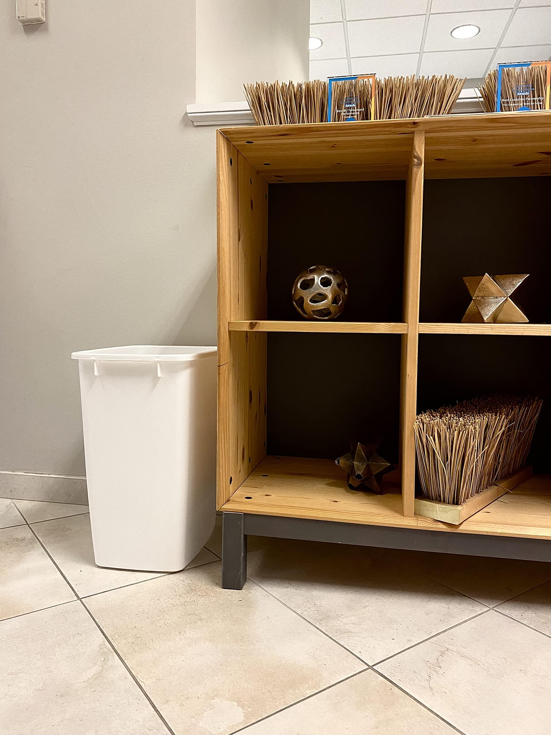 Rectangular Rubbermaid trash can fits neatly beside toilet and cabinet in tight spaces.