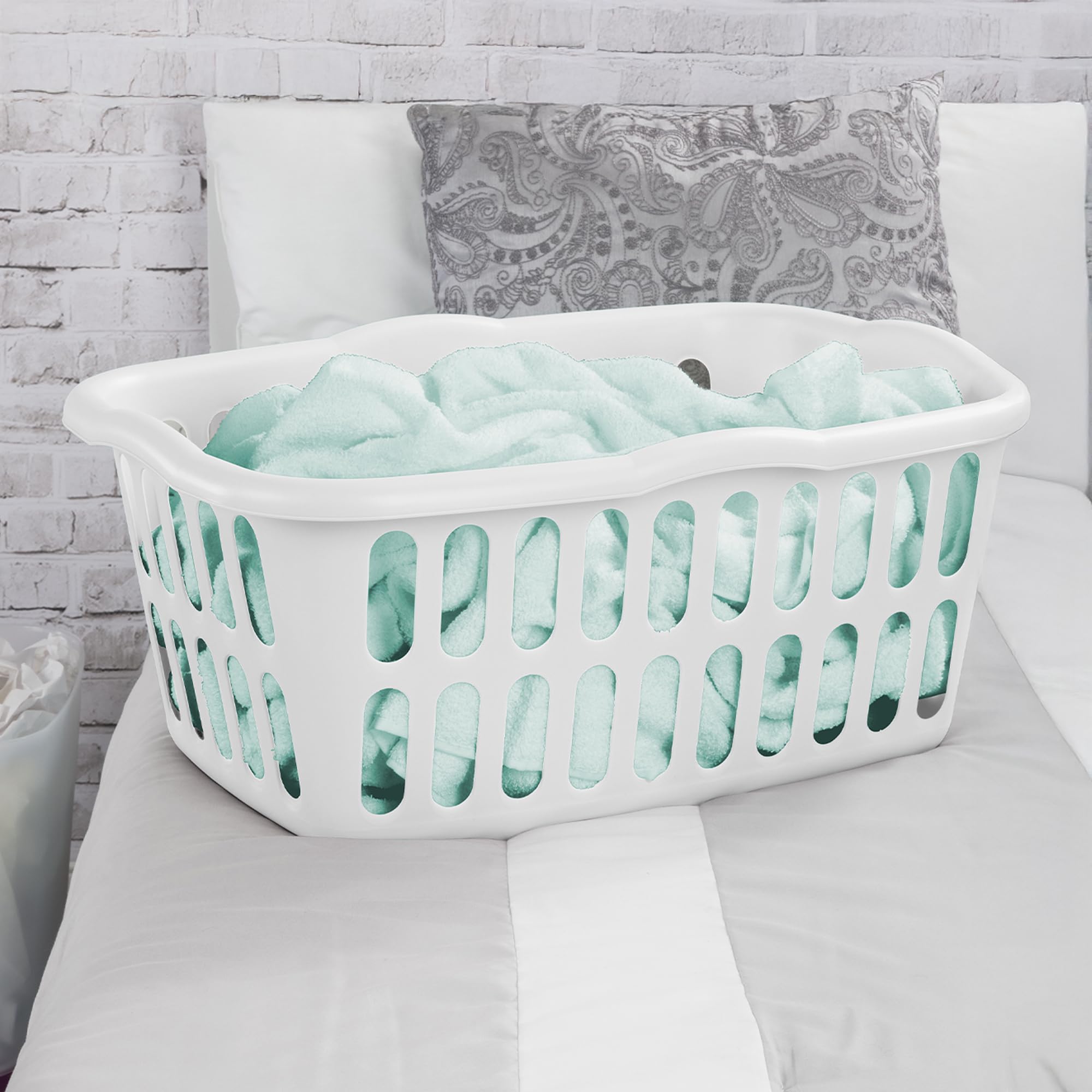 Sterilite white basket in a bedroom for organized laundry storage.