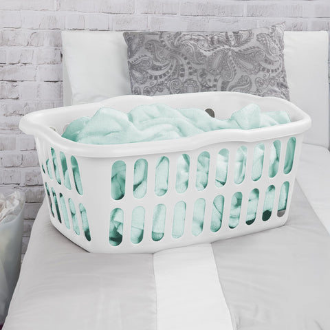 Sterilite white basket in a bedroom for organized laundry storage.