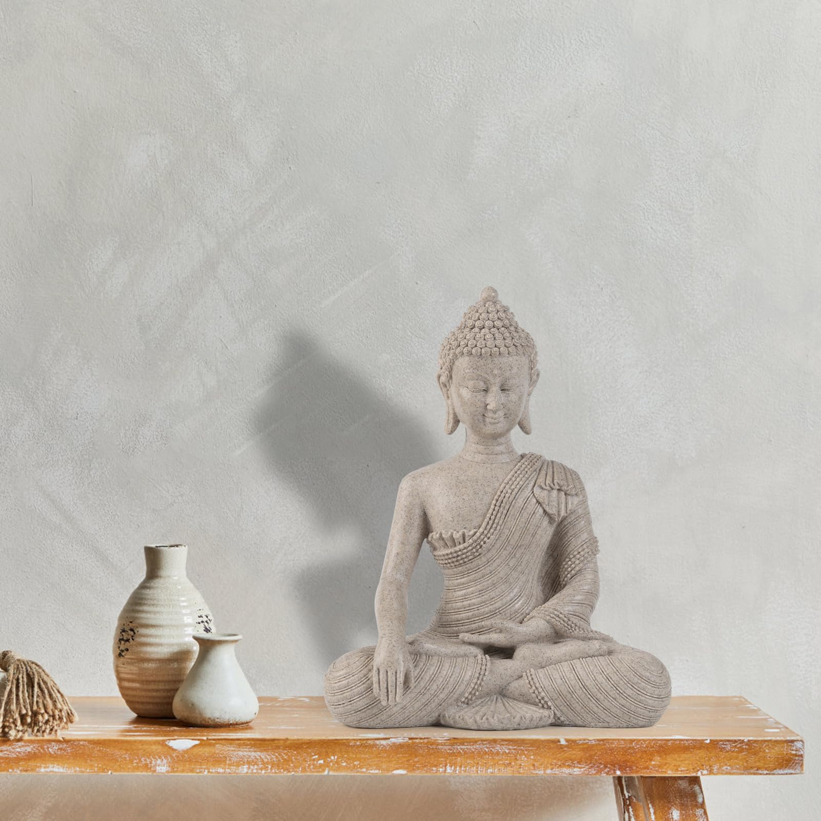 Suoedd Buddha statue on desk or shelf for zen-inspired decor.