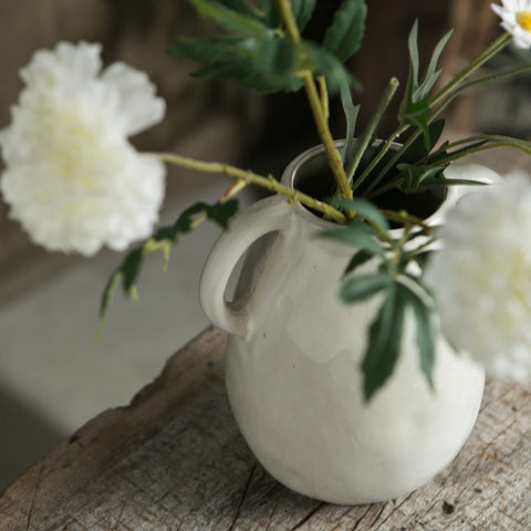 Tanvecle vase with faux flowers creating a chic centerpiece for dining.