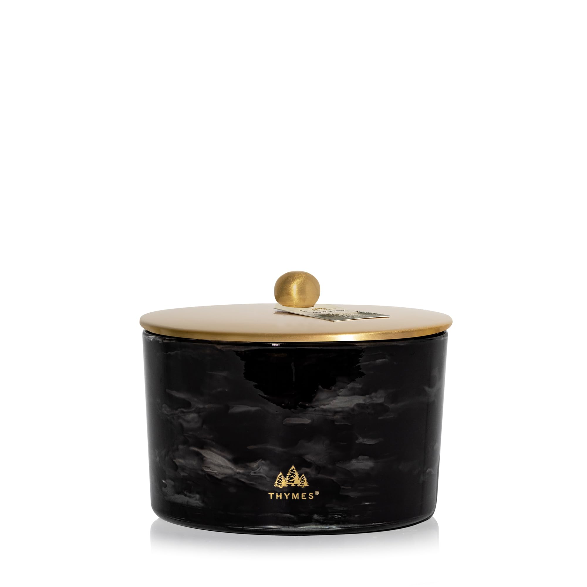 Thymes Noir Woods candle close-up highlighting smoky notes for cozy living room ambiance.