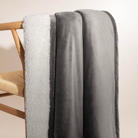 UGG Bliss Throw Blanket layered on a bed for warmth