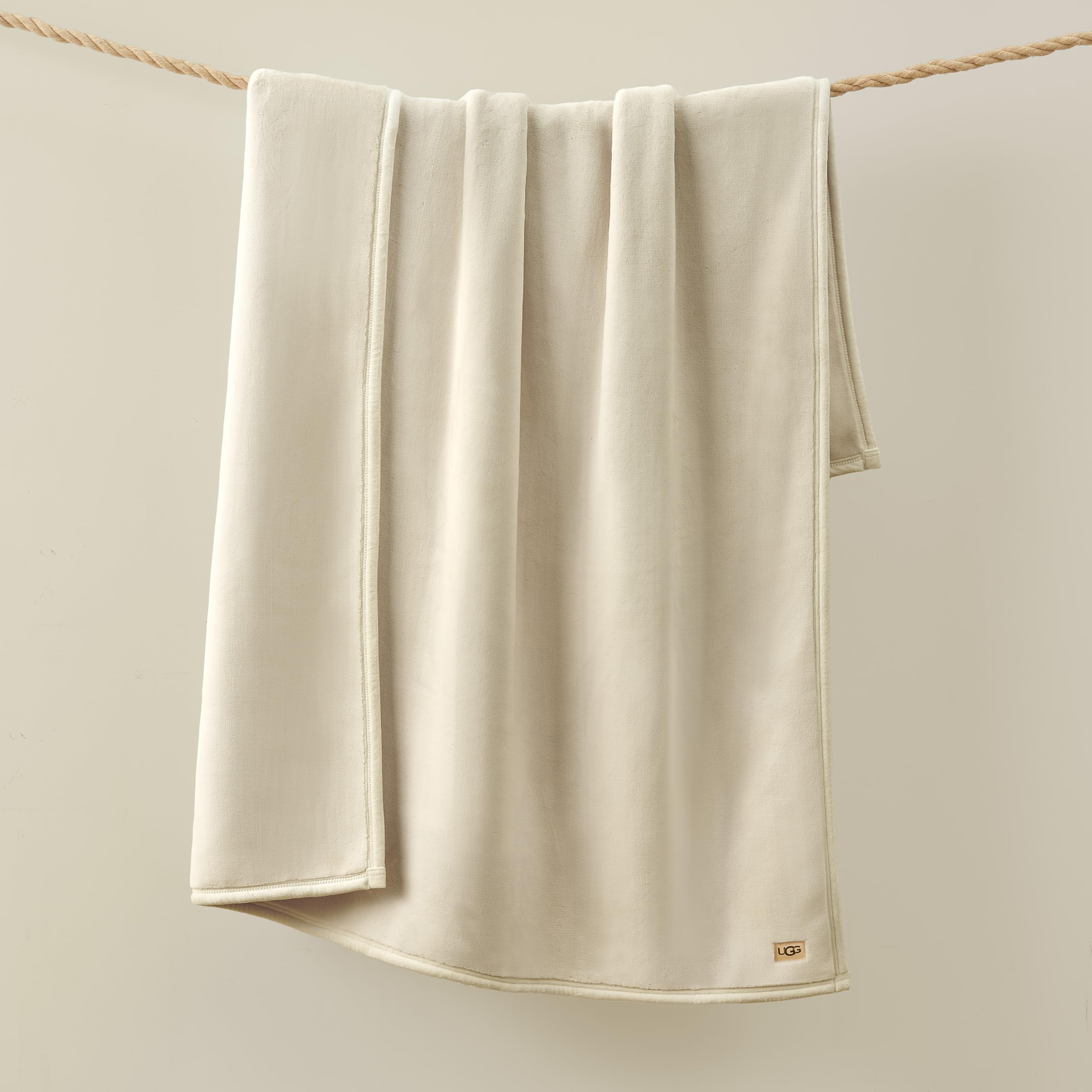 UGG Coco Plush Blanket laid across chair, warm, inviting touch