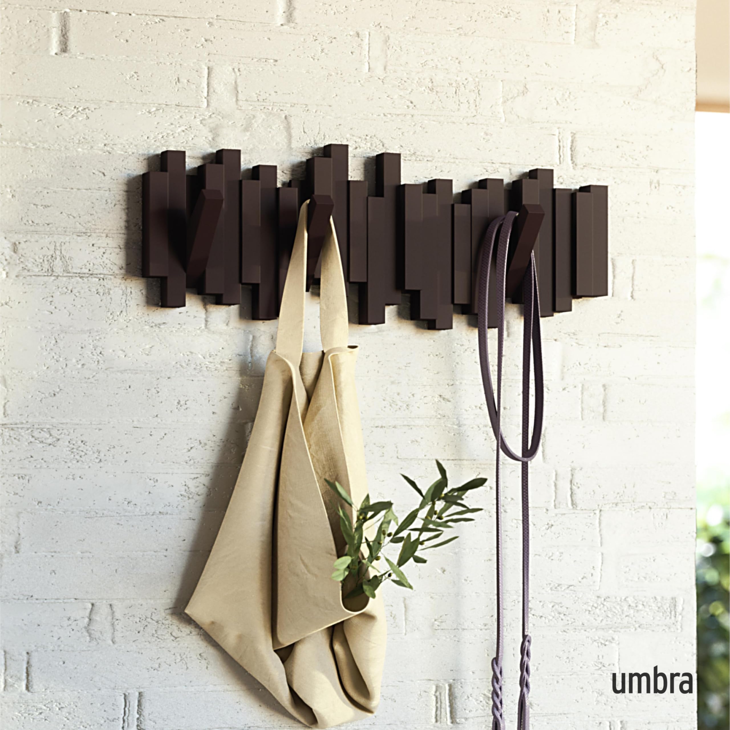 Umbra Sticks espresso retractable pegs in action for coats, bags, and hats.