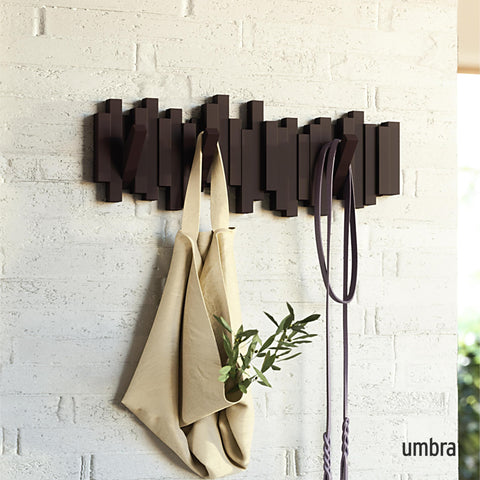 Umbra Sticks espresso retractable pegs in action for coats, bags, and hats.