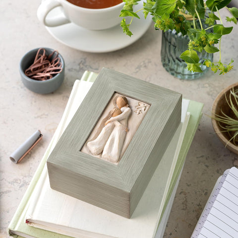 Willow Tree memory box displayed on a shelf adds warm decor.