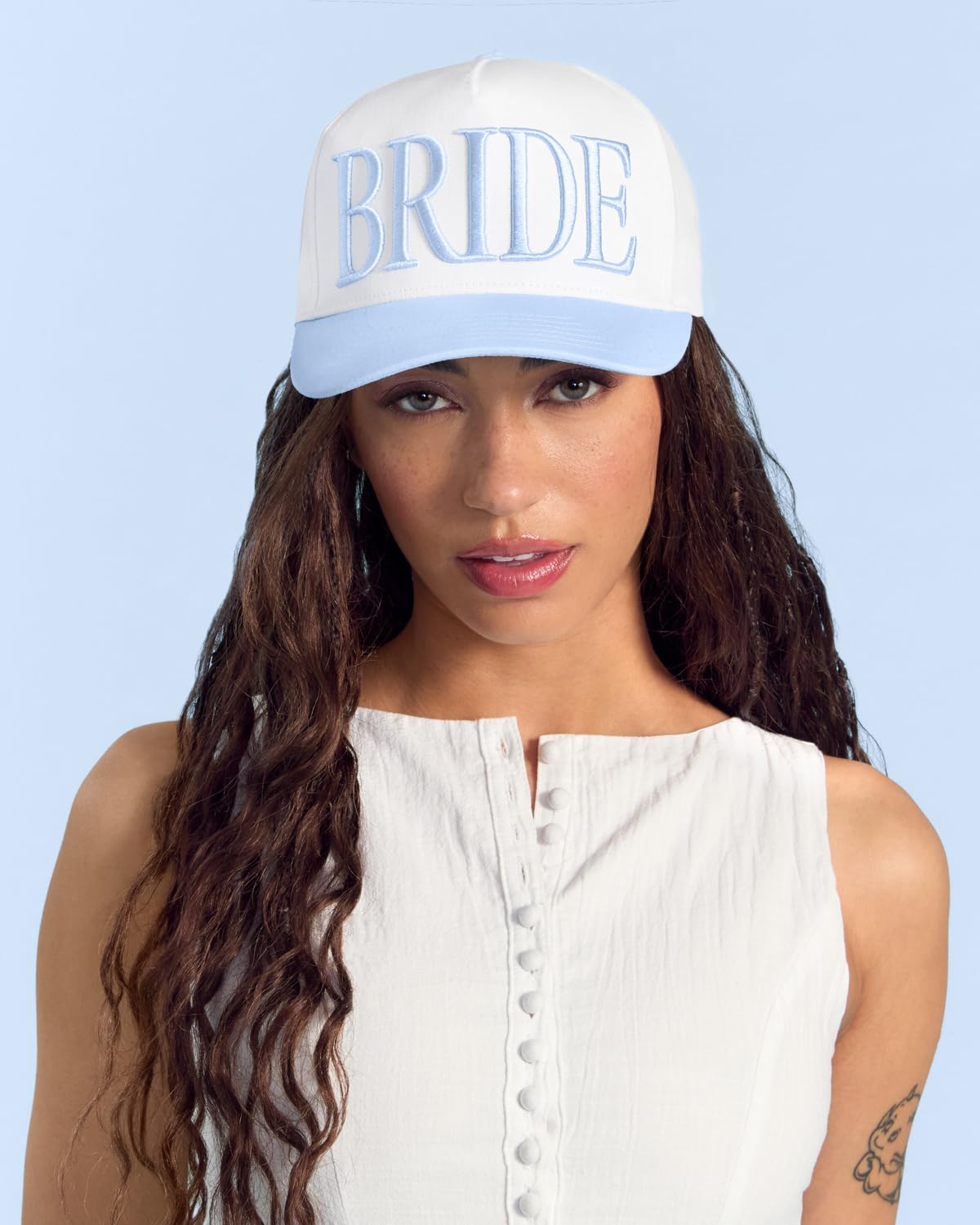 xo Fetti blue embroidery on white hat adds bridal flair.